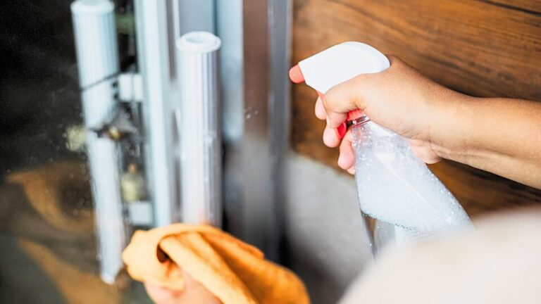 Person cleaning and disinfecting office door handles for workplace hygiene