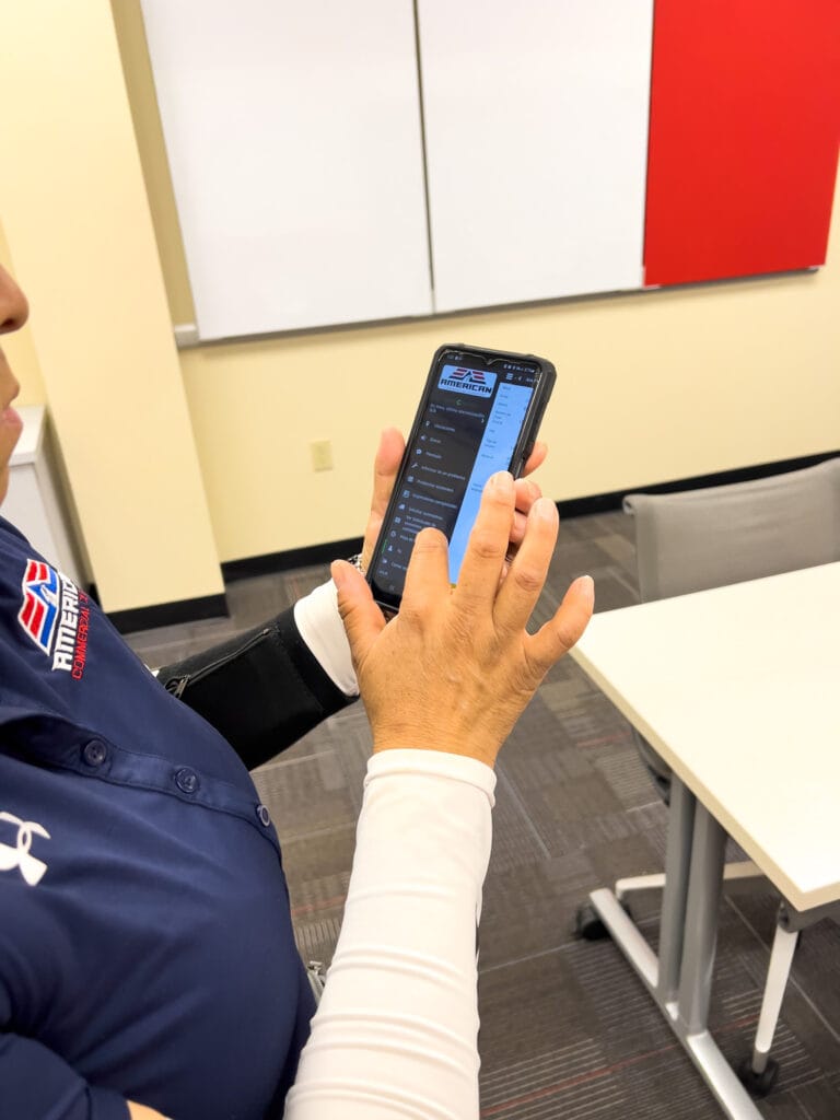 Commercial cleaner using phone to access CleanSmarts app at American Commercial Cleaning