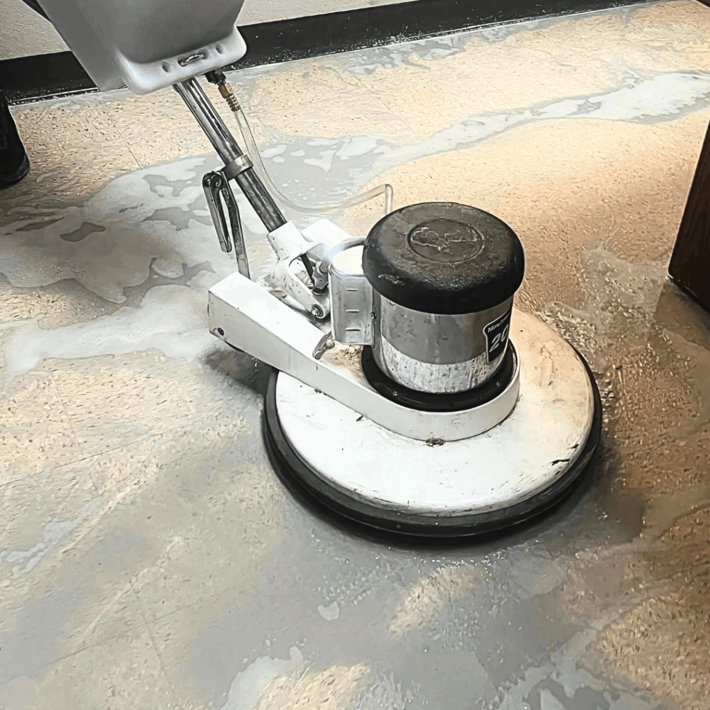 Industrial facility floor being stripped and waxed by cleaning crew