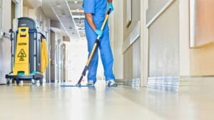 American Commercial Cleaning staff performing professional janitorial services in a school hallway with lockers and bright lighting, ensuring a clean and safe learning environment.