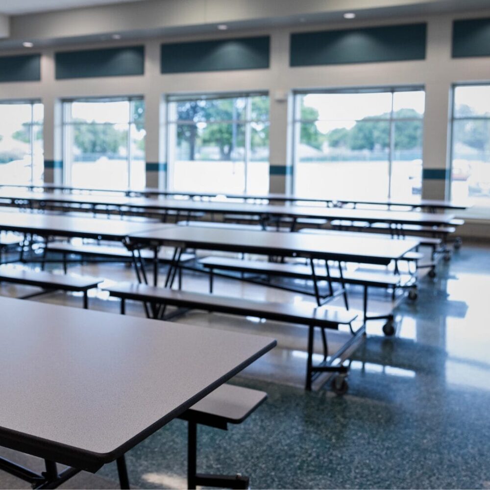 Clean and spacious cafeteria with rows of tables and chairs arranged neatly, bright lighting, and an open layout designed for dining and socializing.